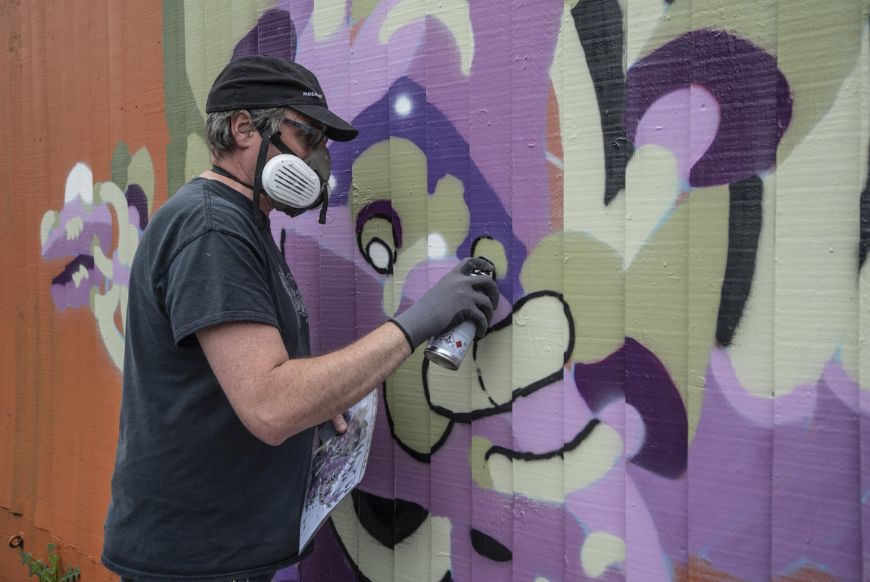 a man with a gas mask painting on a wall with a spray can